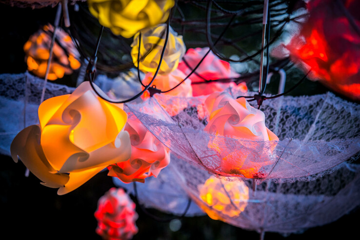 Bunte, dekorative Lampen hängen in kunstvollen Formen, umgeben von zarten Spitzenstoffen.