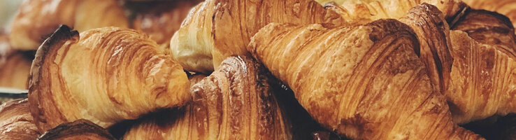 Frische, goldbraune Croissants auf einem silbernen Tablett in einem Hotelbuffet.