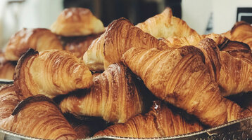 Frische, goldbraune Croissants auf einem silbernen Tablett in einem Hotelbuffet.