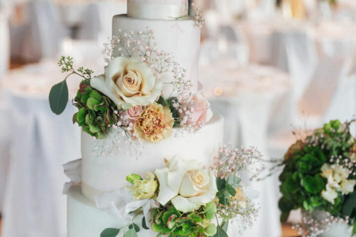 Weiße Hochzeitstorte mit Blumen dekoriert, im elegant gedeckten Saal des ATLANTIC Hotel Heidelberg.