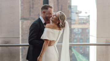 Bride and groom smiling at each other on a terrace of the ATLANTIC Grand Hotel Bremen, historic architecture in the background.