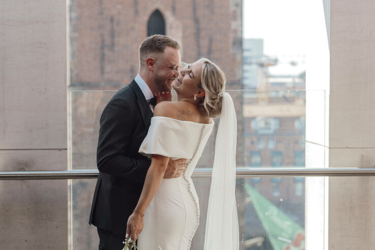 Brautpaar lächelt sich auf einer Terrasse des ATLANTIC Grand Hotel Bremen an, im Hintergrund historische Architektur.