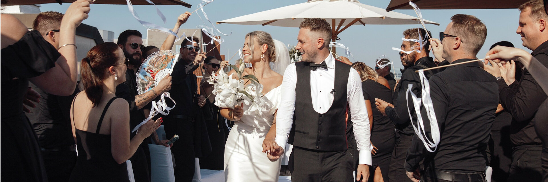 Wedding couple leaving an open-air ceremony at the ATLANTIC Grand Hotel Bremen, surrounded by cheering guests.
