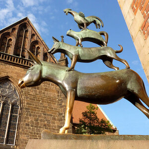 The Bremen Town Musicians Bronze statue of the Bremen Town Musicians in front of a historic brick façade, blue sky in the background.
