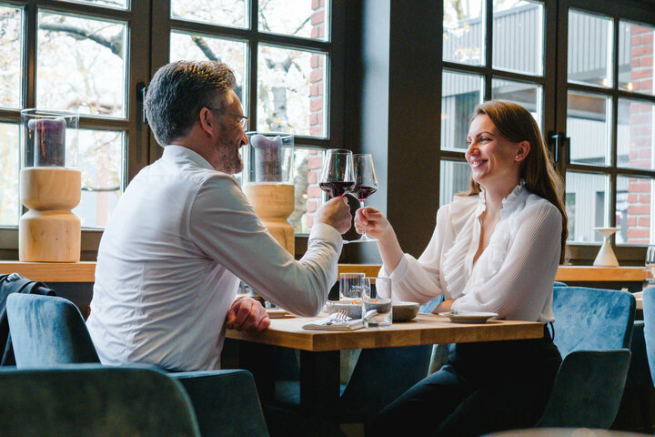 Dining at the ATLANTIC Hotel Landgut Horn Bremen Couple toasting with wine glasses in the elegant restaurant of the ATLANTIC Hotel Landgut Horn.