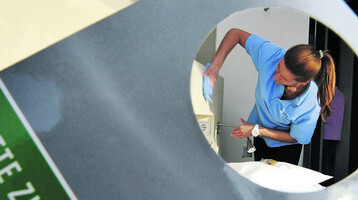 ATLANTIC Hotel SAIL City – Pressemitteilung "Probiotische Reinigung" Hotelangestellte reinigt ein Zimmer im ATLANTIC Hotel Sail City, gesehen durch ein Türschild mit "Bitte Zimmer reinigen".