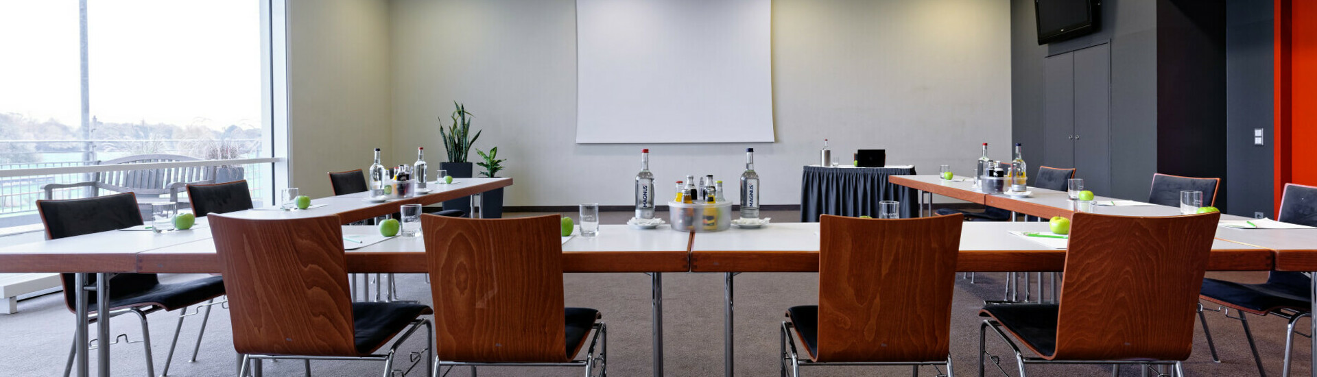 Moderner Konferenzraum mit U-förmiger Bestuhlung, Projektionsleinwand und Tageslicht im ATLANTIC Hotel Galopprennbahn.