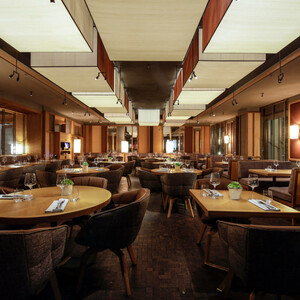 Elegantes Restaurant im LOUIS Hotel München mit stilvoll gedeckten Tischen und gemütlicher Beleuchtung.