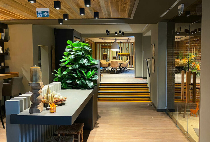 Elegante Hotellobby mit Holzelementen, Pflanzen, Sitzbereich und dekorativen Kerzen im ATLANTIC Hotel Landgut Horn Bremen.