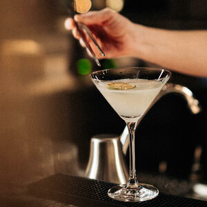 Ein eleganter Cocktail mit Limettenscheibe wird an einer stilvollen Bar zubereitet.