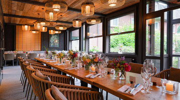 Elegantes Restaurant mit gedecktem Holztisch, Blumenarrangements und stilvollen Hängelampen im ATLANTIC Hotel Landgut Horn.
