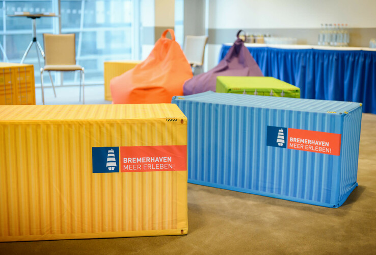 Bunte Sitzsäcke und Container im ATLANTIC Hotel Sail City, Bremerhaven, mit "Bremerhaven Meer Erleben!"-Logo.