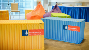 Team Camp im ATLANTIC Hotel Sail City Bunte Sitzsäcke und Container im ATLANTIC Hotel Sail City, Bremerhaven, mit "Bremerhaven Meer Erleben!"-Logo.