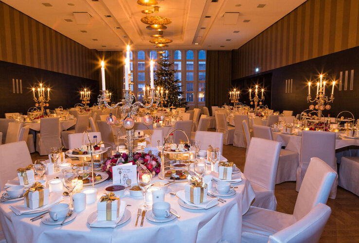 Eleganter Festsaal im ATLANTIC Grand Hotel Bremen, festlich gedeckte Tische mit Kerzenleuchtern und Weihnachtsbaum im Hintergrund.