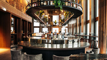 15 High Roofbar on the 15th floor of the ATLANTIC Hotel Heidelberg Modern hotel bar with round counter, stylish lighting, plants and bottles of spirits at the ATLANTIC Hotel Heidelberg.