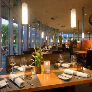 Modernes Hotelrestaurant mit elegant gedeckten Tischen, großen Fenstern und stimmungsvoller Beleuchtung im ATLANTIC Hotel Universum.