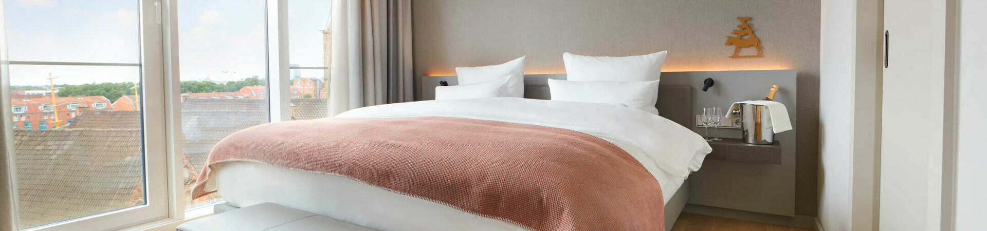 Balcony Suite sleeping area at the Atlantic Grand Hotel Bremen Bright hotel room with large bed, floor-to-ceiling windows and city view at the ATLANTIC Grand Hotel Bremen.