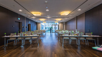 Moderner Konferenzraum im ATLANTIC Grand Hotel Bremen mit Tischen, Stühlen und Blick auf eine Fensterfront.