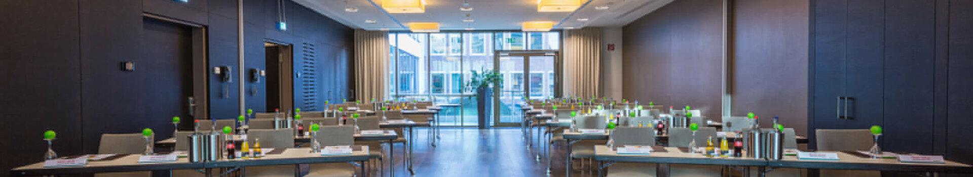 Moderner Konferenzraum im ATLANTIC Grand Hotel Bremen mit Tischen, Stühlen und Blick auf eine Fensterfront.