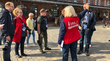 Tourist guide in a red vest shows a group of visitors the sights in Bremerhaven.