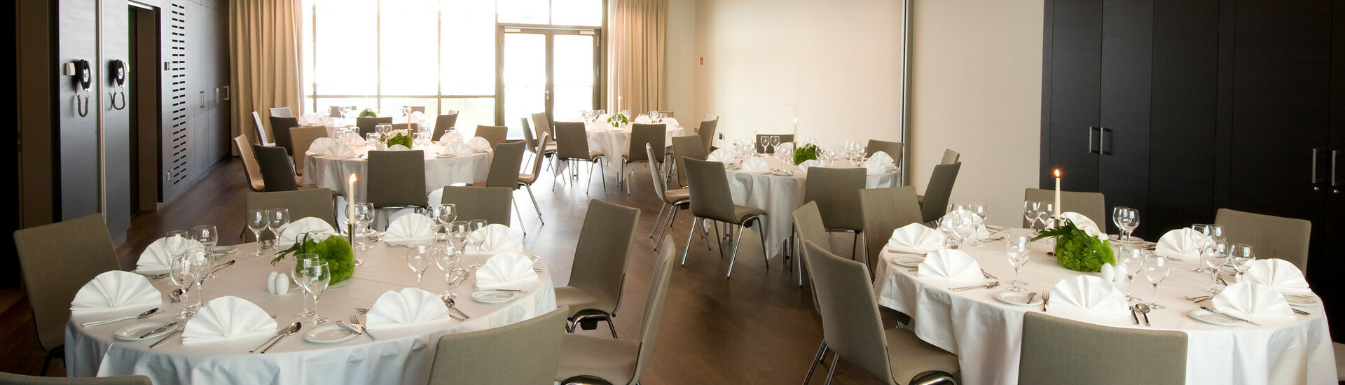 Eleganter Bankettsaal im ATLANTIC Grand Hotel Bremen mit runden, festlich gedeckten Tischen und modernen Stühlen.