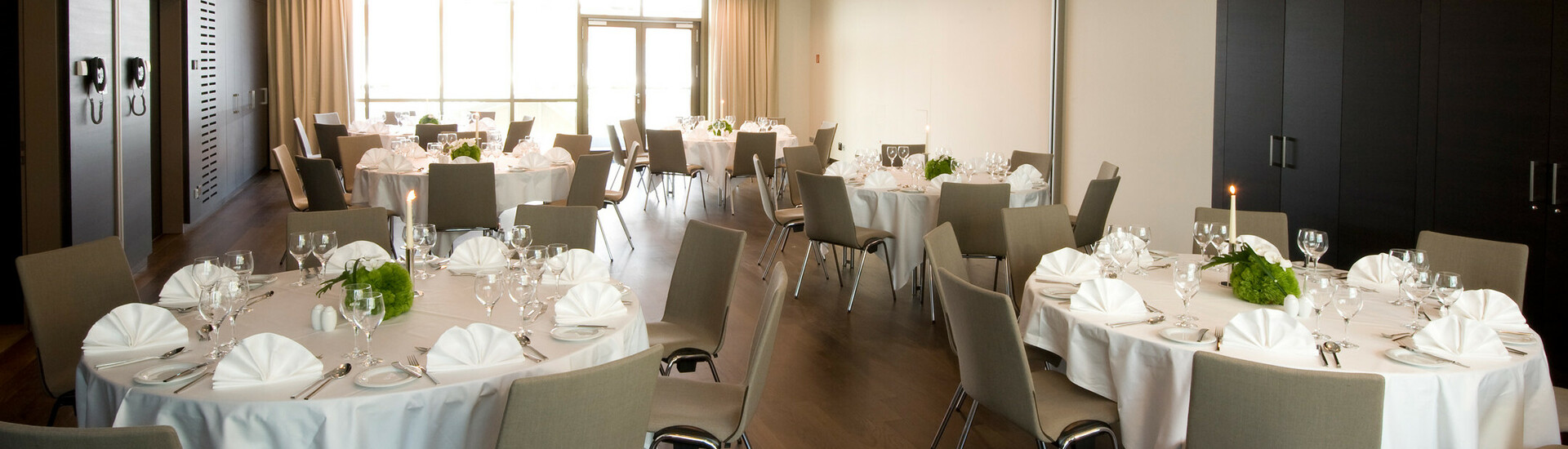 Elegant banquet hall in the ATLANTIC Grand Hotel Bremen with round, festively laid tables and modern chairs.