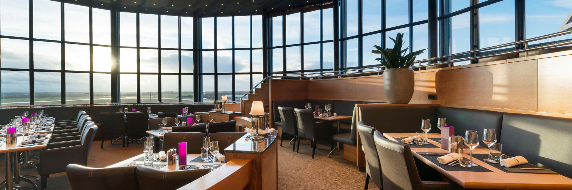 Modernes Restaurant mit Panoramafenstern, elegant gedeckten Tischen und stilvoller Beleuchtung im ATLANTIC Hotel Airport Bremen.