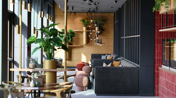 Deli Lounge im ATLANTIC Hotel Heidelberg Moderner Hotel-Loungebereich mit stilvollen Sofas, Pflanzen und Hängelampen im ATLANTIC Hotel Heidelberg.