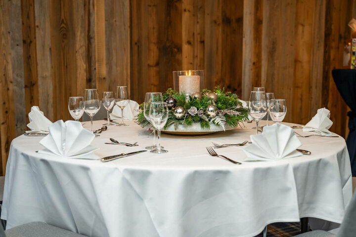 Celebrate Christmas at the ATLANTIC Hotel Landgut Horn Festively laid table with white tablecloth, candle arrangement and folded napkins at the ATLANTIC Hotel Landgut Horn.