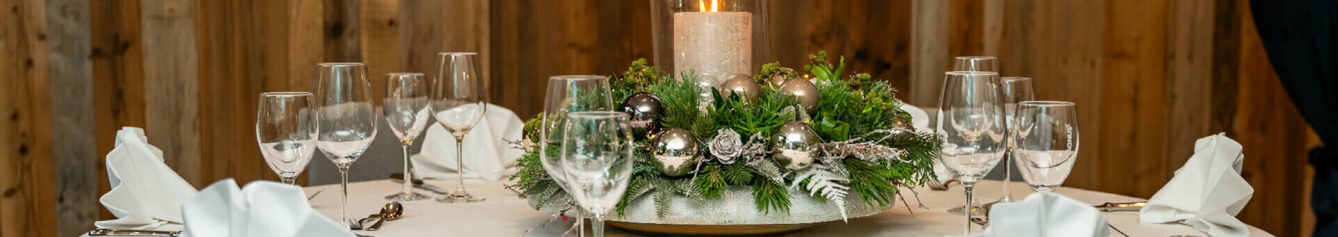 Weihnachten feiern im ATLANTIC Hotel Landgut Horn Festlich gedeckter Tisch mit weißer Tischdecke, Kerzenarrangement und gefalteten Servietten im ATLANTIC Hotel Landgut Horn.