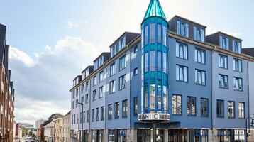 ATLANTIC Hotel Vegesack in Bremen Modernes Hotelgebäude mit blauer Fassade und markantem, gläsernem Turm an einer städtischen Straße.