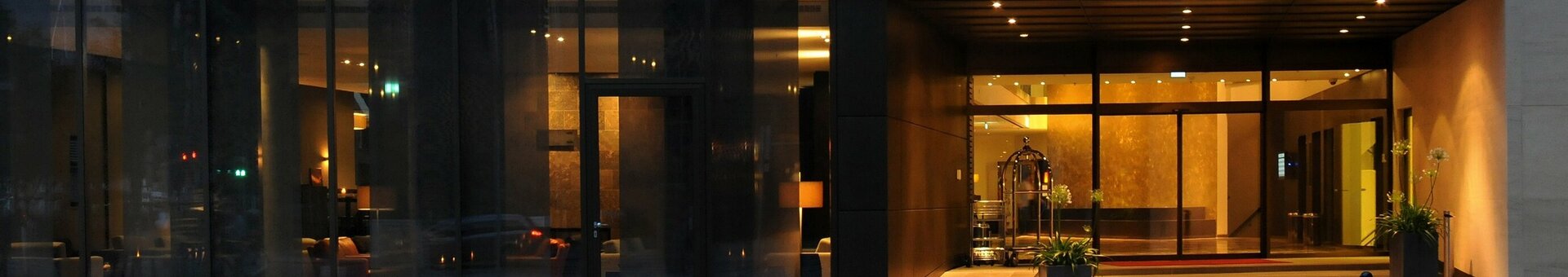 Eingangsbereich des ATLANTIC Grand Hotel Bremen bei Nacht, beleuchtet mit großen Fenstern und moderner Fassade.