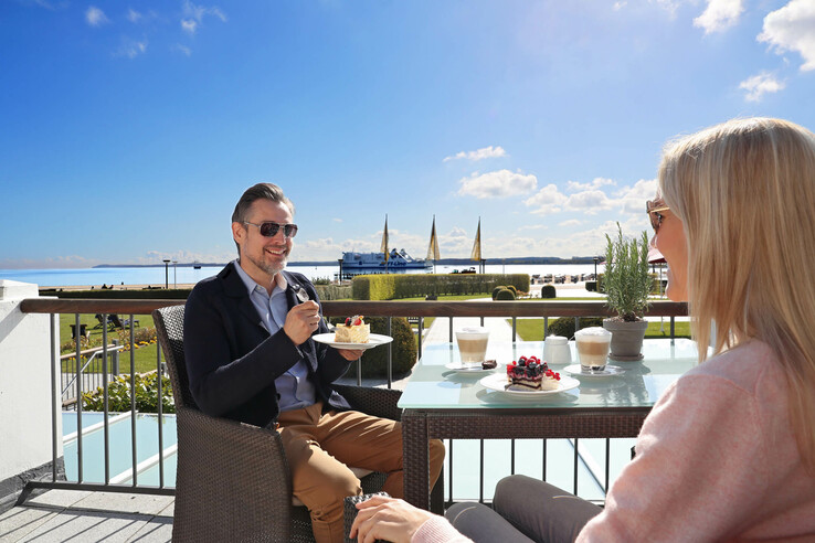 Paar genießt Kaffee und Kuchen auf Terrasse mit Meerblick im ATLANTIC Grand Hotel Travemünde.