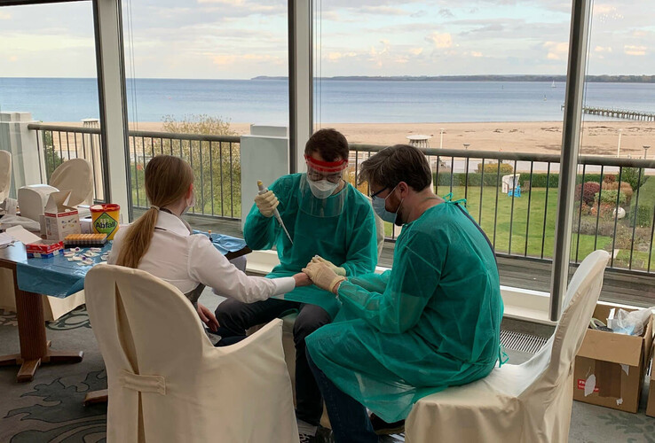 Medizinisches Personal in Schutzkleidung führt Tests in einem Raum mit Meerblick im ATLANTIC Grand Hotel Travemünde durch.