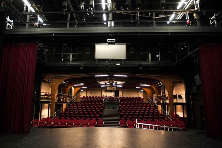 Theater stage with red curtain, view of empty auditorium with red rows of seats and balcony. © bremer shakespeare company