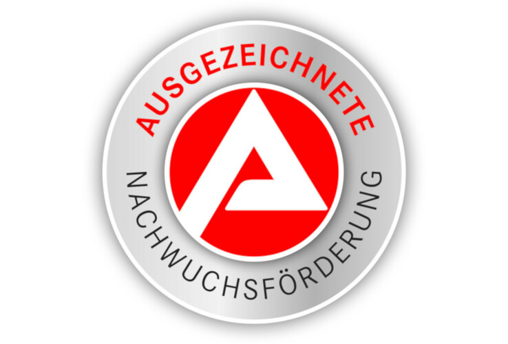 Rundes Logo mit rotem Kreis und weißem "A", umgeben von "Ausgezeichnete Nachwuchsförderung" in Schwarz und Rot.