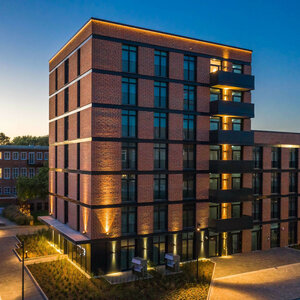 Brick hotel at dusk, illuminated, with modern architecture and large windows.