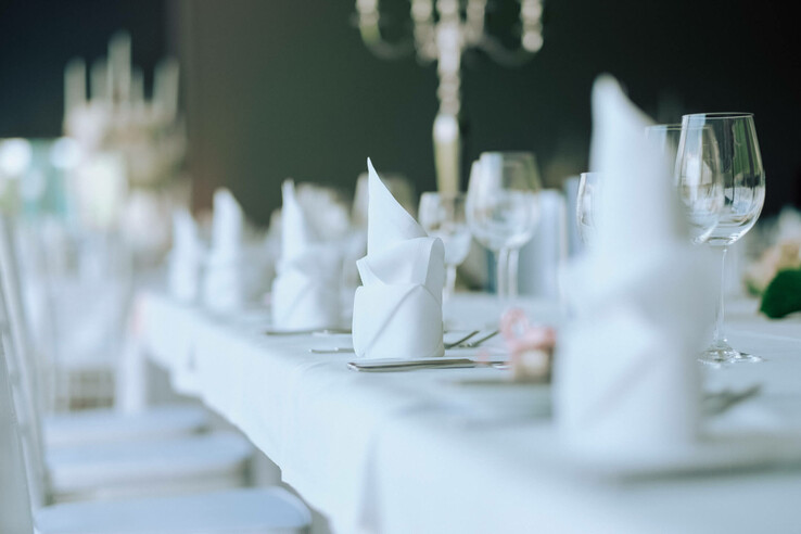 Elegant, festively laid table with white napkins and wine glasses at the ATLANTIC Hotel Galopprennbahn Bremen.