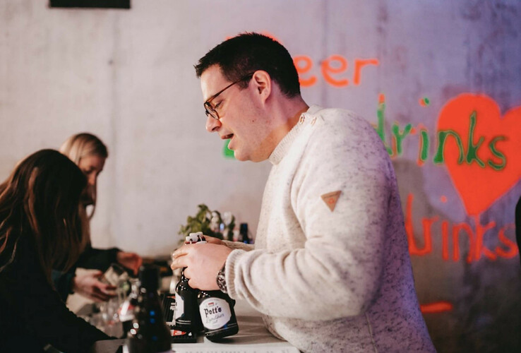 ATLANTIC Hotel Münster Pop-up Party zum Valentinstag Person schenkt Getränke an einer Bar ein, im Hintergrund bunte Neon-Schriftzüge.