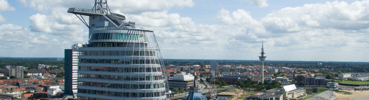 ATLANTIC Hotel Sail City in Bremerhaven, modernes Hochhaus am Wasser mit Blick auf die Stadt und die Küste.