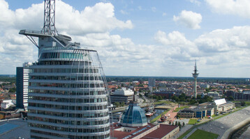 ATLANTIC Hotel Sail City in Bremerhaven, modernes Hochhaus am Wasser mit Blick auf die Stadt und die Küste.