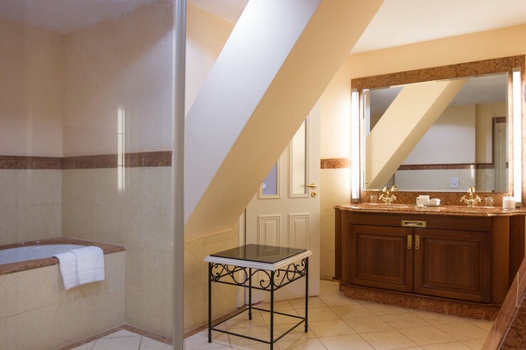 Elegantes Badezimmer mit Doppelwaschbecken, Badewanne und Dachschräge im ATLANTIC Grand Hotel Travemünde.