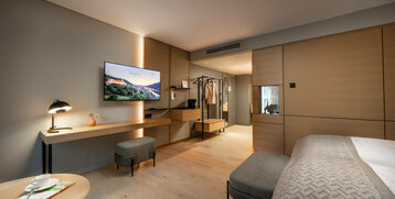 Modernes Hotelzimmer mit Doppelbett, Schreibtisch, Flachbild-TV und Garderobe im ATLANTIC Hotel Heidelberg.