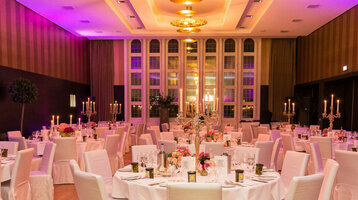Seating  for a wedding in the Goldener Saal of the ATLANTIC Grand Hotel Bremen  Elegant banquet hall in the ATLANTIC Grand Hotel Bremen with round, festively laid tables and candlesticks.