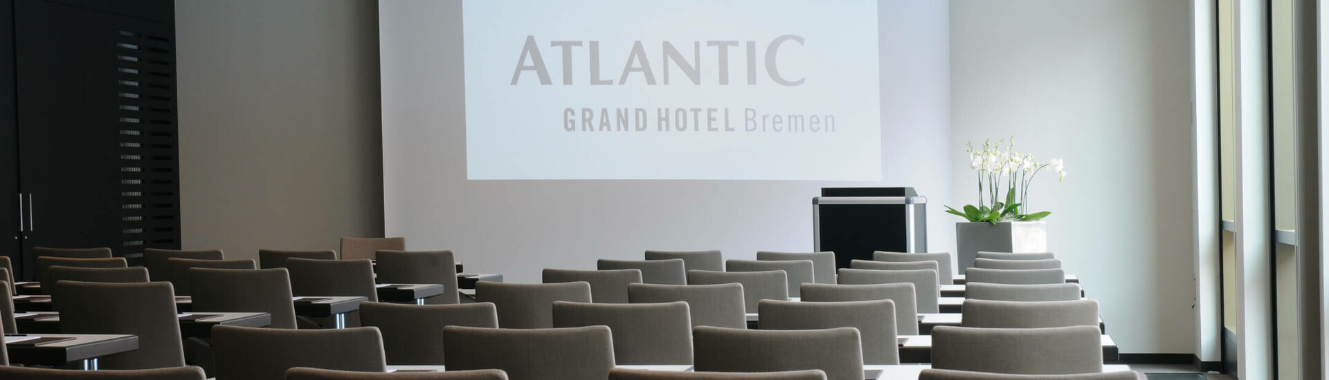 Conference 1 in the ATLANTIC Grand Hotel Bremen with parliamentary seating Modern conference room in the ATLANTIC Grand Hotel Bremen with screen and rows of chairs.