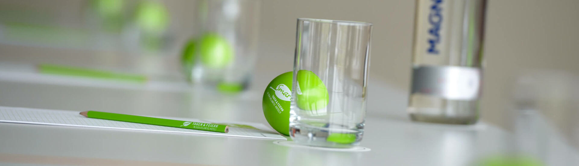 Tagen im ATLANTIC Hotel Galopprennbahn Konferenztisch mit grünen Bällen, Gläsern, Stiften und Wasserflasche im ATLANTIC Hotel Galopprennbahn Bremen.
