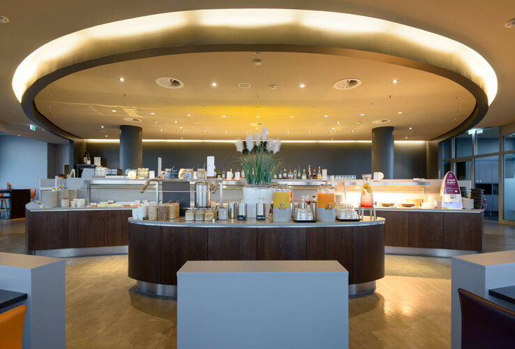 Modern breakfast buffet at the ATLANTIC Hotel Sail City with drinks dispensers, cereals and decorative plants.