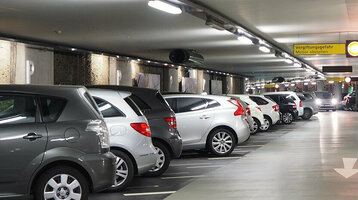 Helle Tiefgarage mit geparkten Autos und Wegweiser zum Ausgang Rathaus/Münsterplatz im ATLANTIC Grand Hotel Bremen.