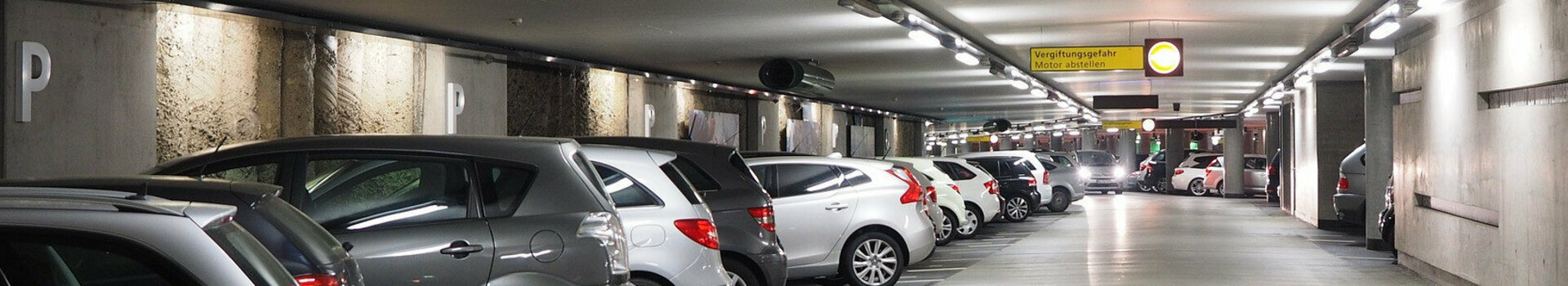 Helle Tiefgarage mit geparkten Autos und Wegweiser zum Ausgang Rathaus/Münsterplatz im ATLANTIC Grand Hotel Bremen.