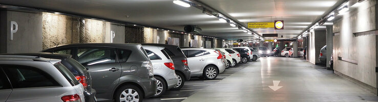Helle Tiefgarage mit geparkten Autos und Wegweiser zum Ausgang Rathaus/Münsterplatz im ATLANTIC Grand Hotel Bremen.